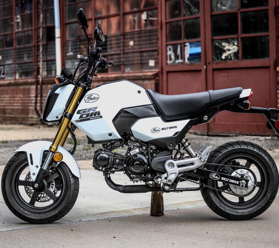 Honda Grom with Gates belt drive parked in front of an industrial building.