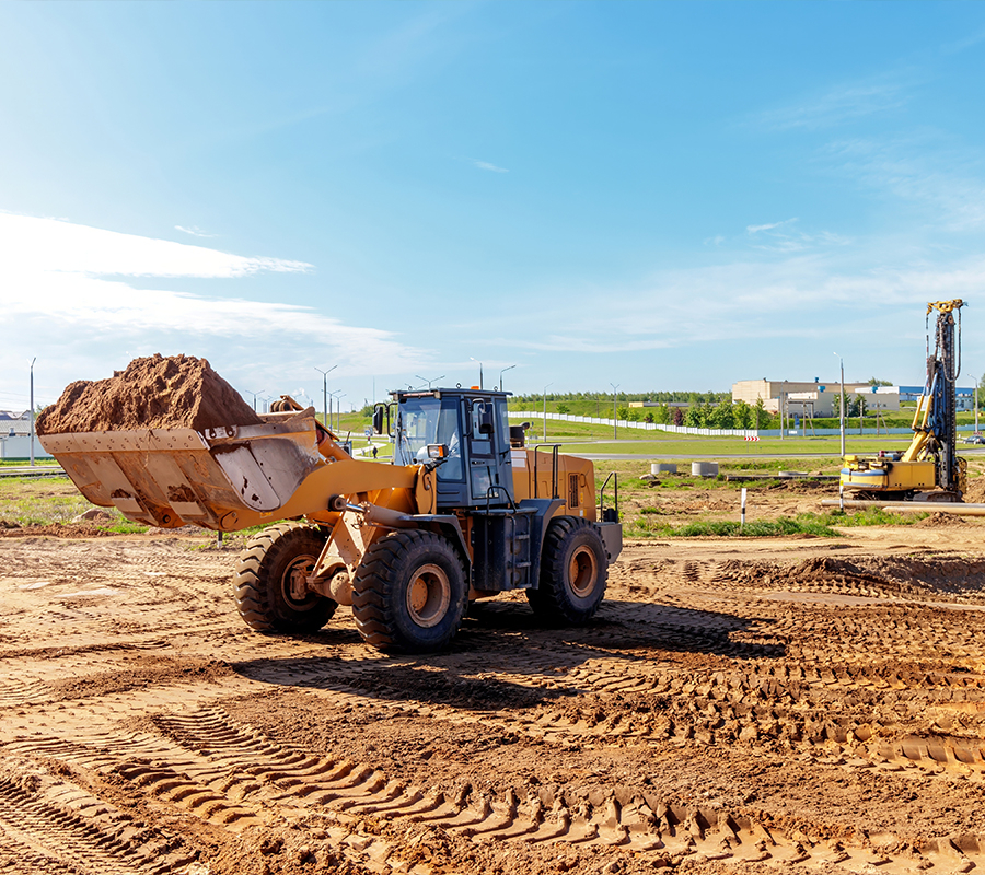 A construction vehicle rests on a dirt field, exemplifying its powerful performance and suitability for construction tasks.
