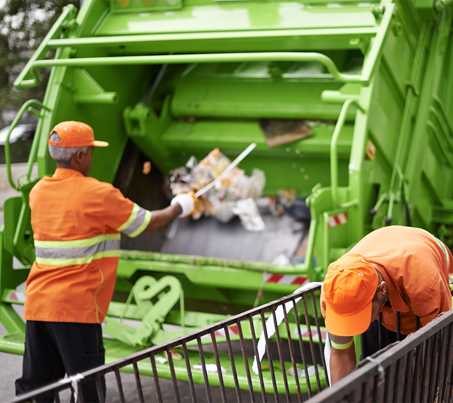 Two men loading waste into a garbage truck, highlighting the truck's performance.
