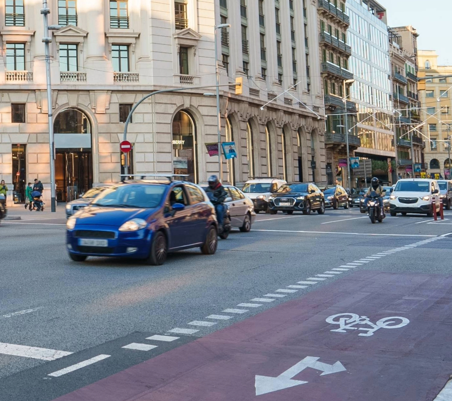 Busy city intersection with cars, motorcycles, and a dedicated bike lane marked on the road