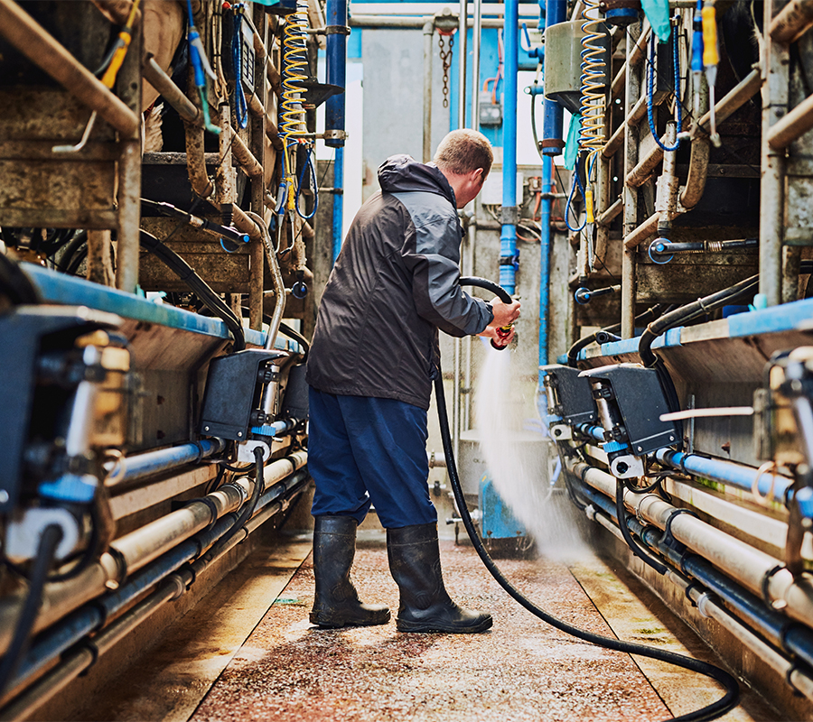 A man sprays water in a industrial setting, keeping it clean and tidy.