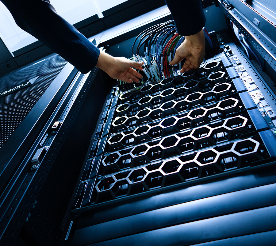full color image of a technician reaching for wires coming out of a server rack