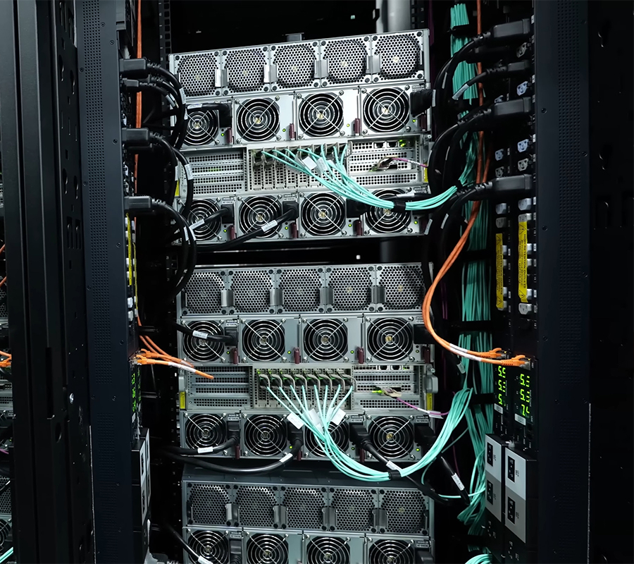 image of black server rack with multiple green and orange telecomms cords