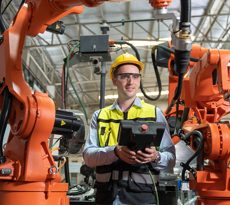 A man stands confidently in front of a futuristic robot, showcasing a blend of human and technological innovation.