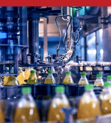Automated beverage bottling line filling plastic bottles with liquid and green caps in a food and beverage manufacturing facility.
