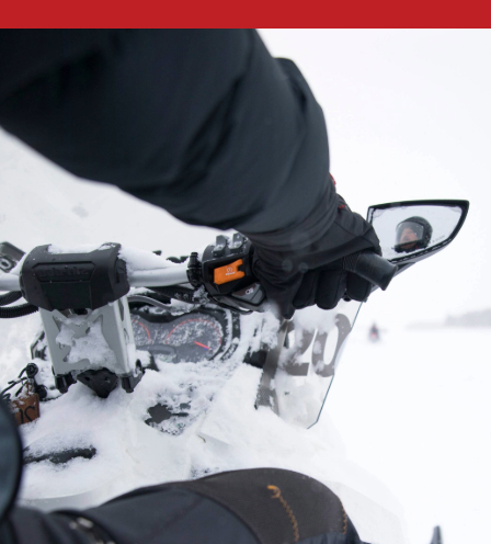 A close-up of a person riding a snowmobile in snowy conditions