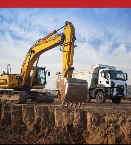 Yellow excavator loading dirt into a white dump truck at a construction site with a clear blue sky in the background.