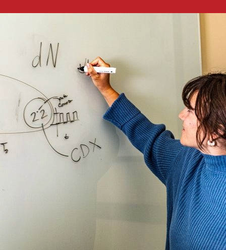 Woman working engineering equations on whiteboard