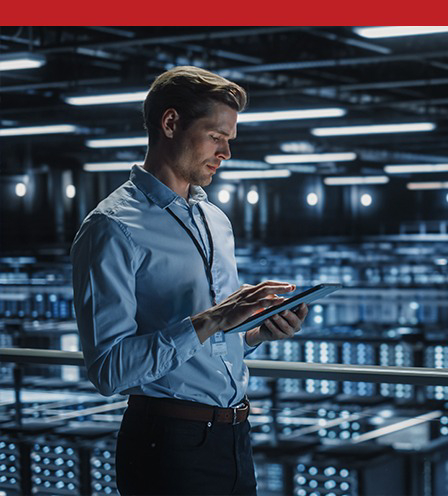 man standing in a well-lit data center checking details on a tablet