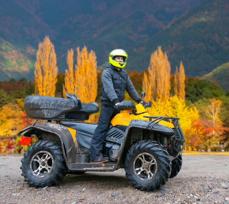 Person riding an ATV in front of autumn foliage