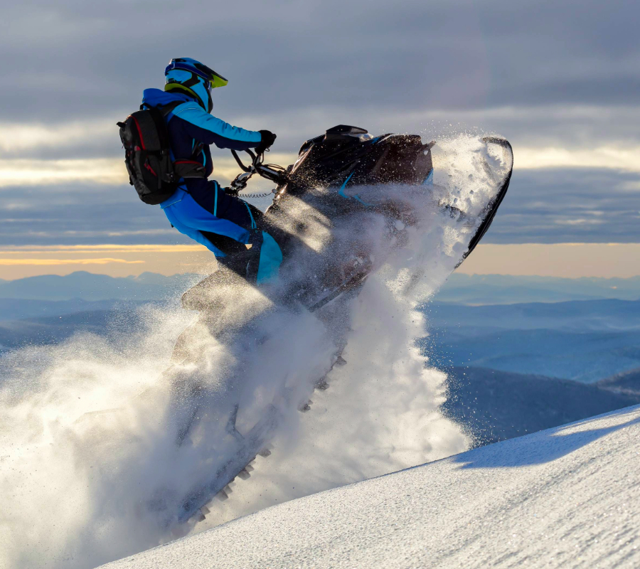 Snowmobile rider launching off a snowy slope