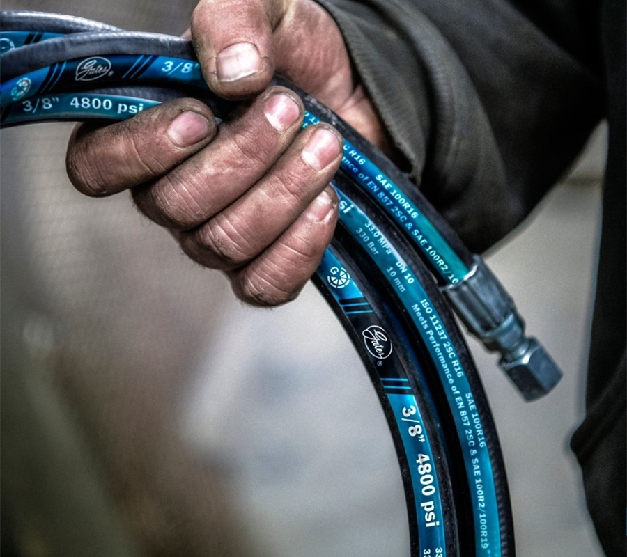 Close-up of a man's hand holding a gates hydraulic hose