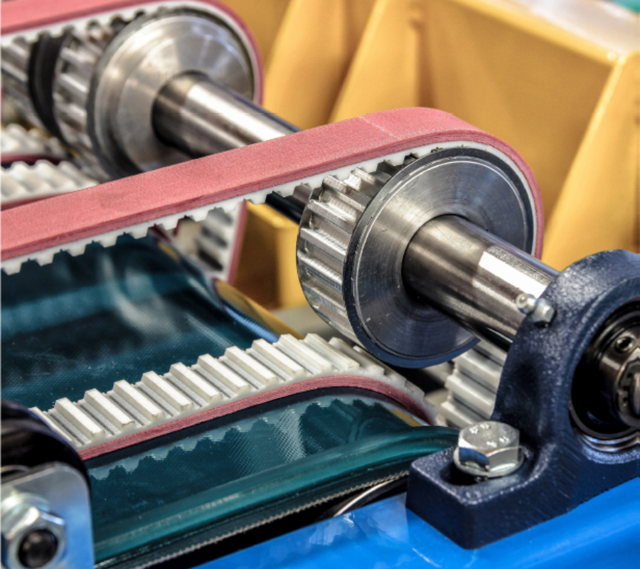 Close-up of TPU timing belts running over pulleys in an industrial manufacturing machine.