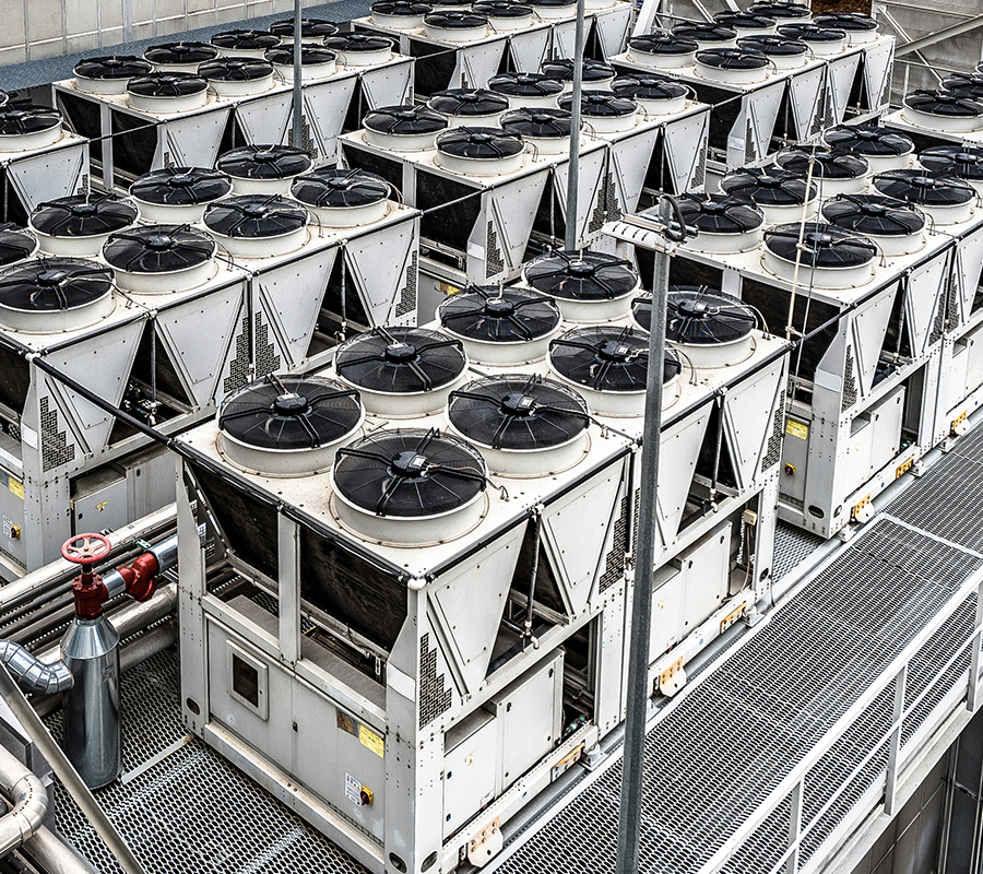 Aerial view of large industrial HVAC rooftop cooling units arranged in rows at a facility