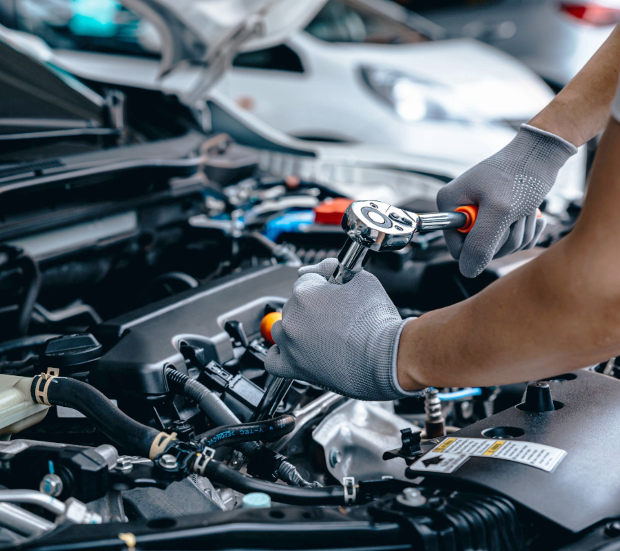 Mechanic using wrench while working on car engine at garage workshop, Car auto services and maintenance check concept.