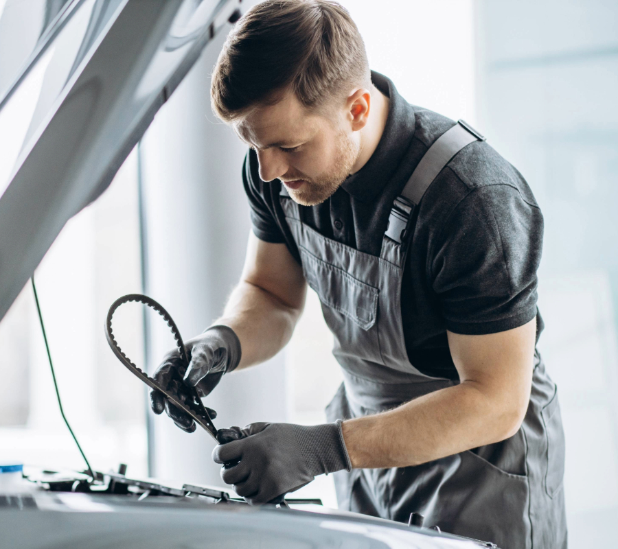 Car mechanic holding a belt while inspecting the car