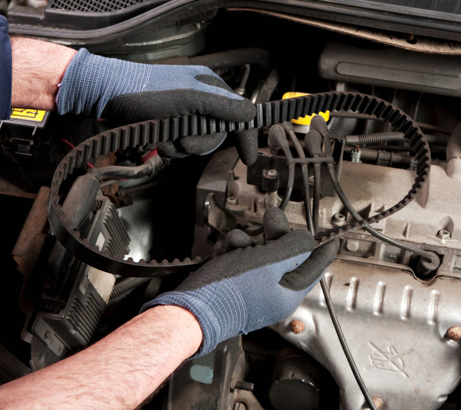 Mechanic holding a belt and repairing a car in the garage