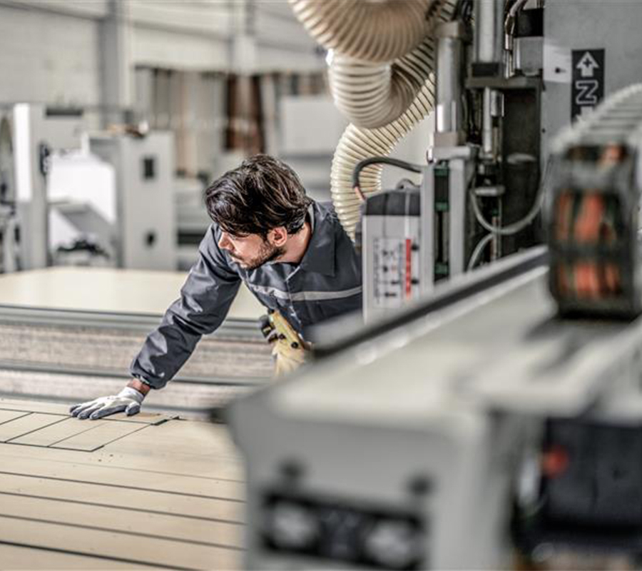 man with dark hair working with large machinery in a well-lit factory setting