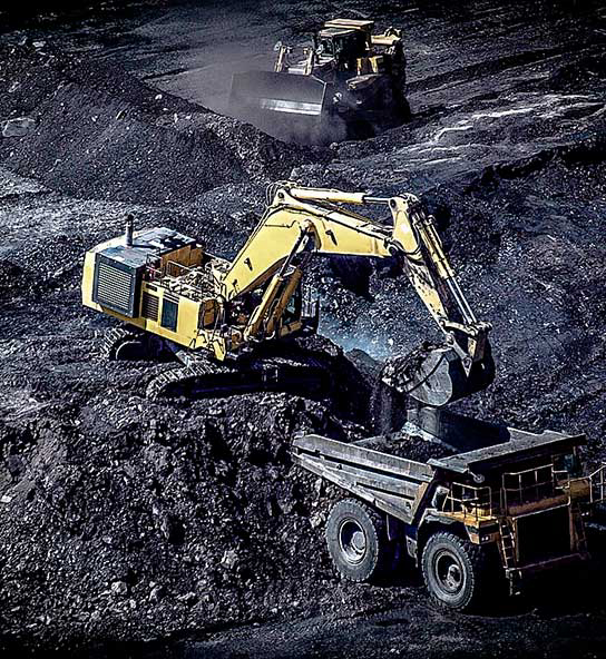 Coal mining equipment operator loading coal into a Dump truck along side an industrial front loader