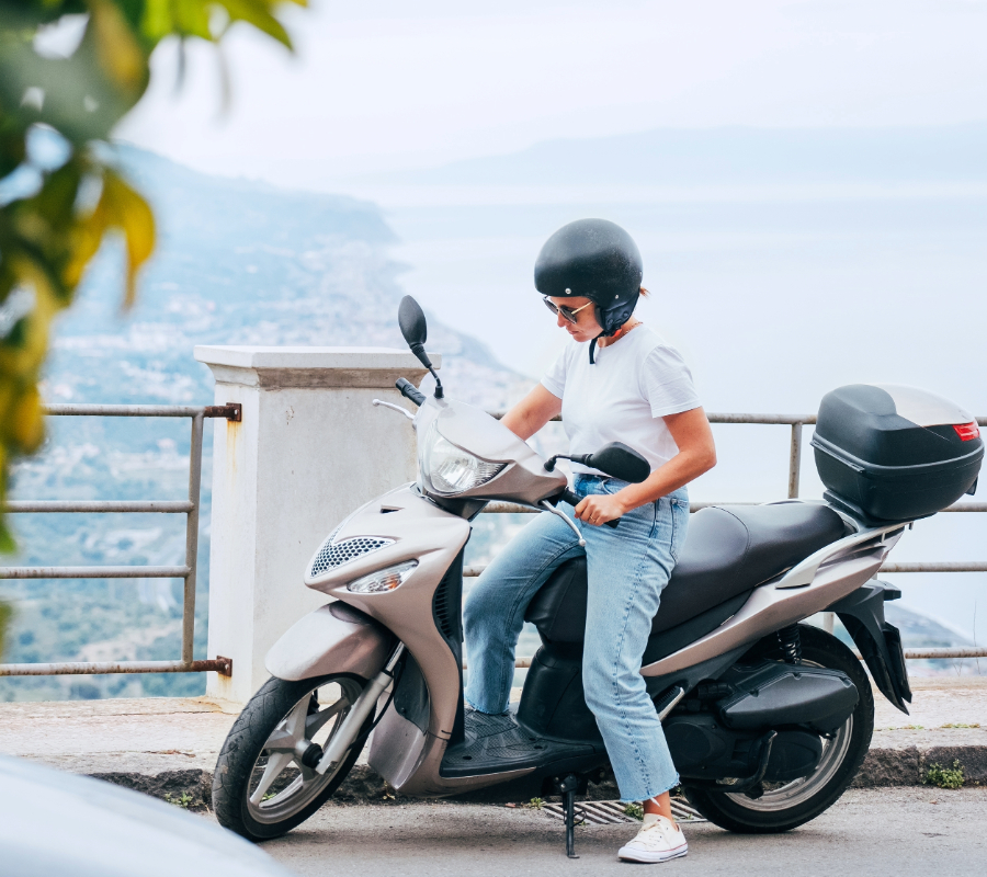 woman in helmet and sunglasses on motor scooter 