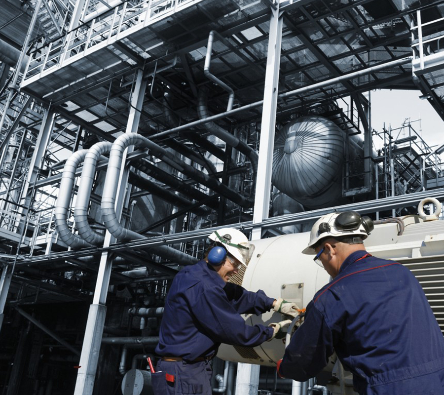 Two maintenance technicians fixing a piece of equipment at an processing plant.