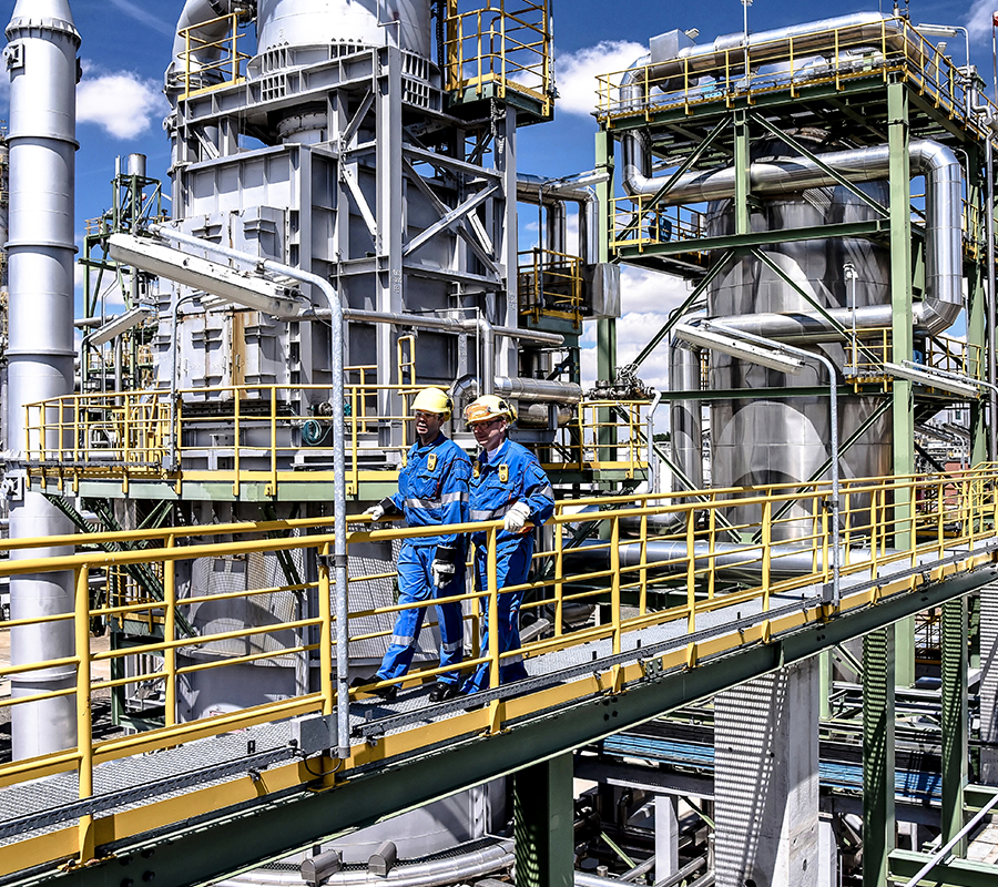 Two maintenance technicians walking on a bridge at a processing plant facility.