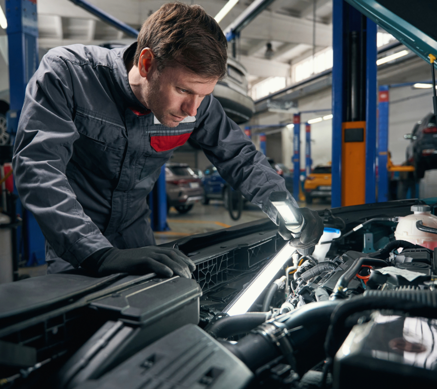 Automotive technician inspecting a vehicle engine during maintenance and diagnostics