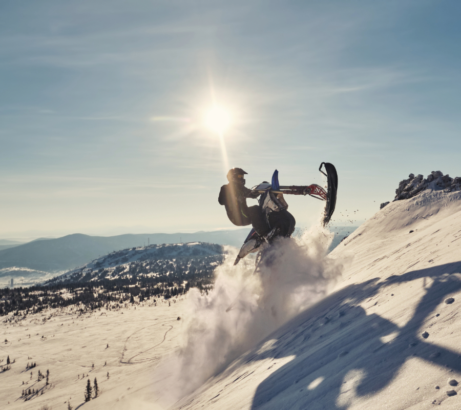 Snowmobile rider climbing a snowy mountainside.