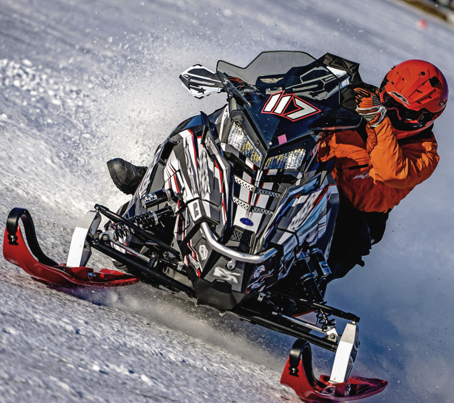Snowmobile rider carving across a snowy slope.