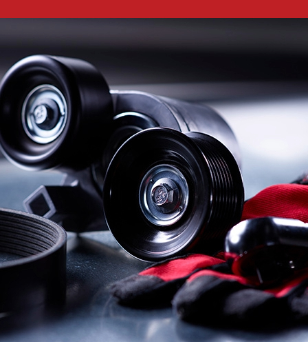 Close-up of Gates belt tensioner with pulley wheels and a drive belt.