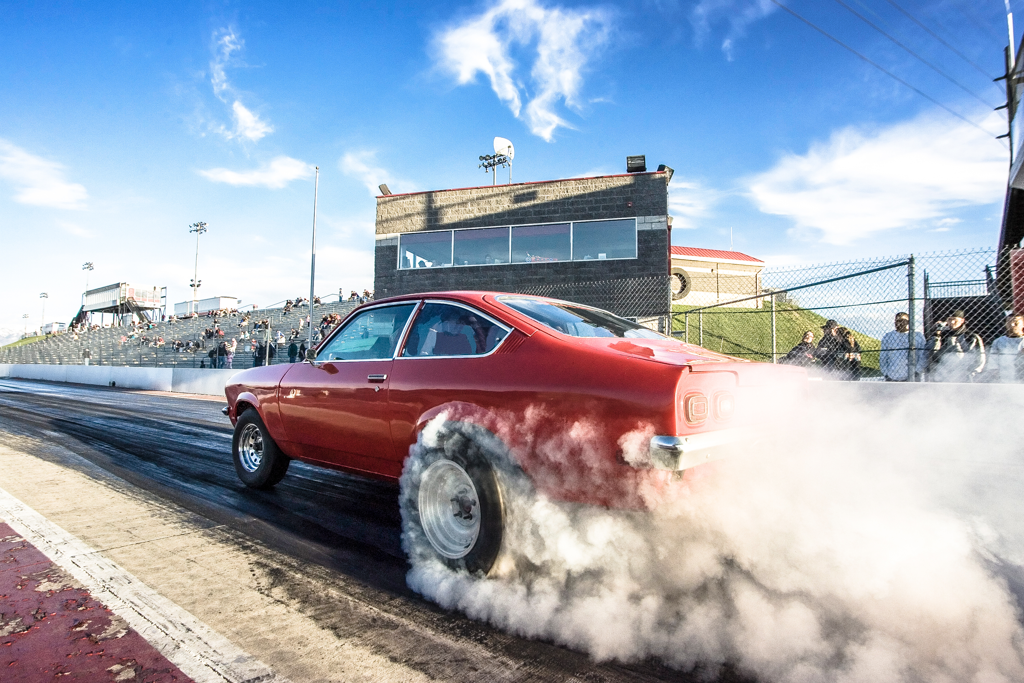 Red car on race track with smoking tires